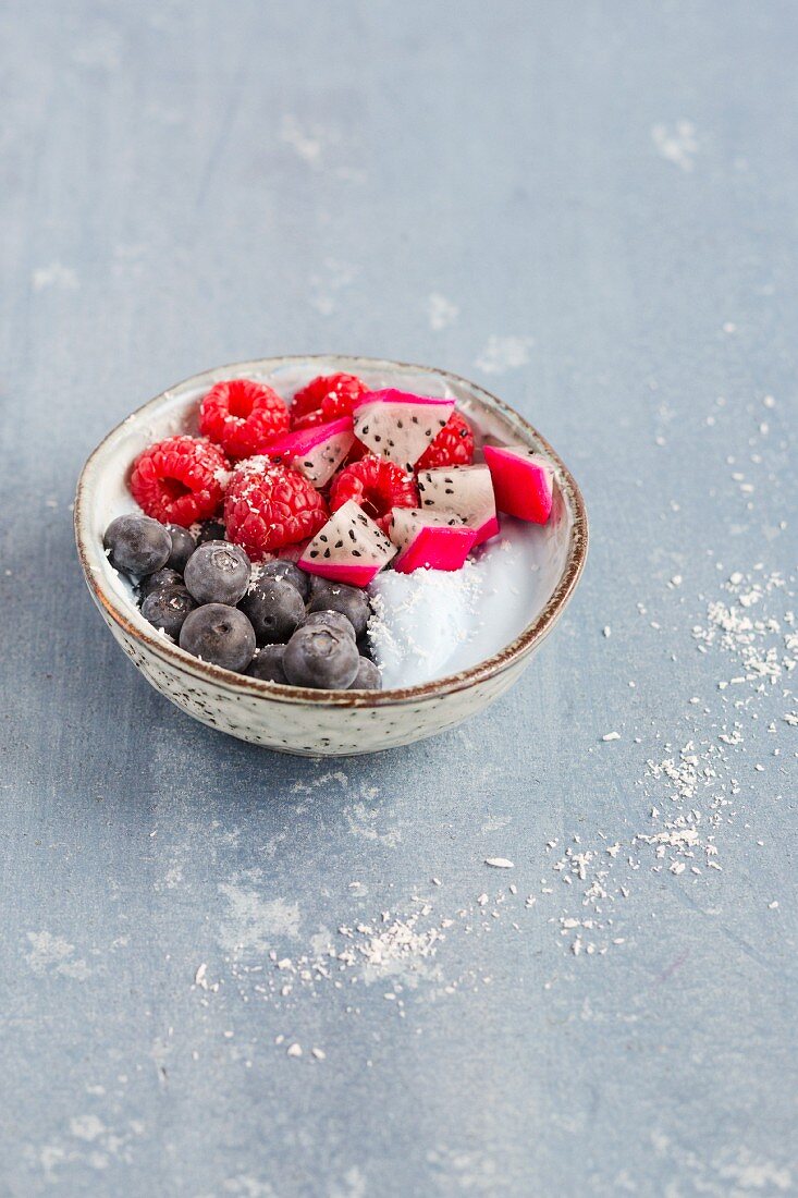 A smurf latte bowl with raspberries, papaya, blueberries and coconut
