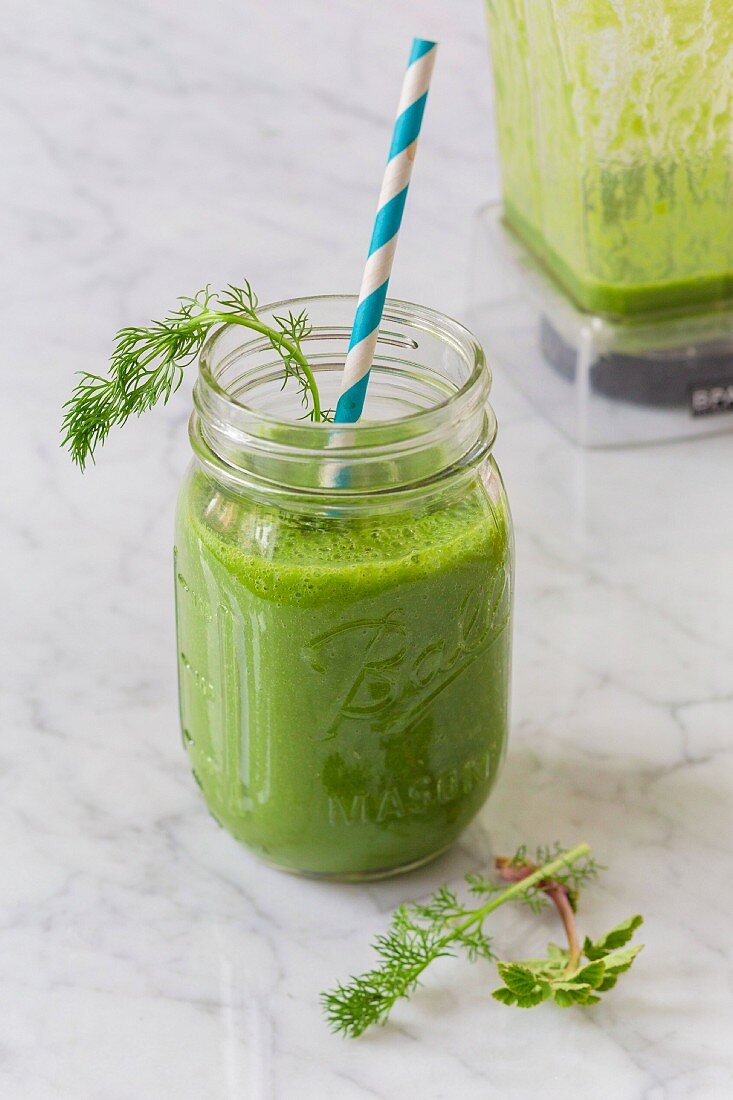 Grüner Wildkräuter-Smoothie mit Strohhalm im Glas