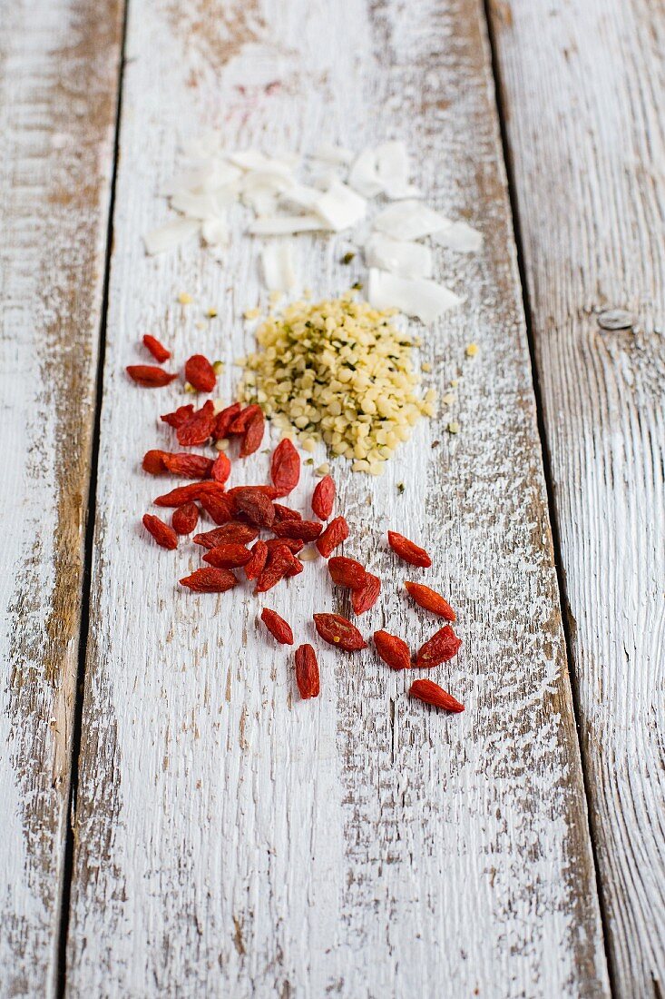 Goji berries, hemp seeds and coconut chips on a wooden background