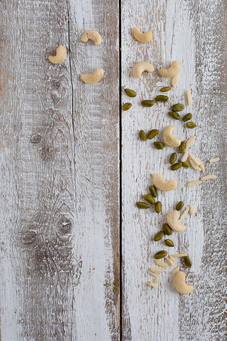 Almond slivers, cashews and pistachios on a wooden background (seen from above)