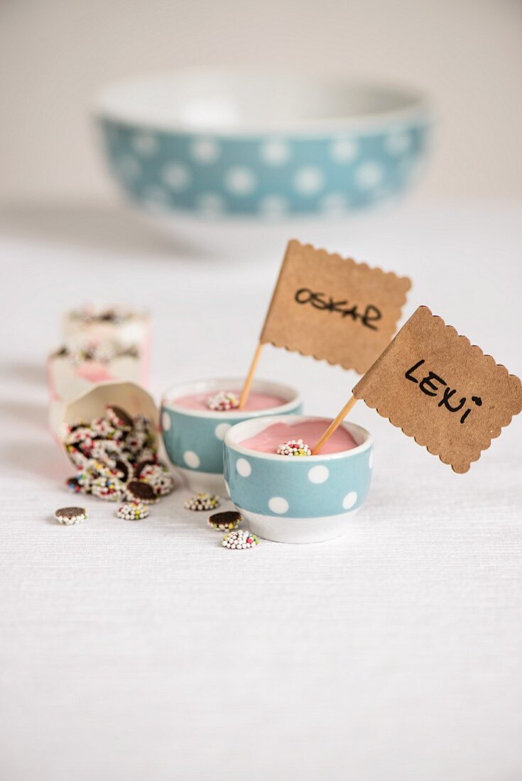 Pink crème desserts in small bowls with labels