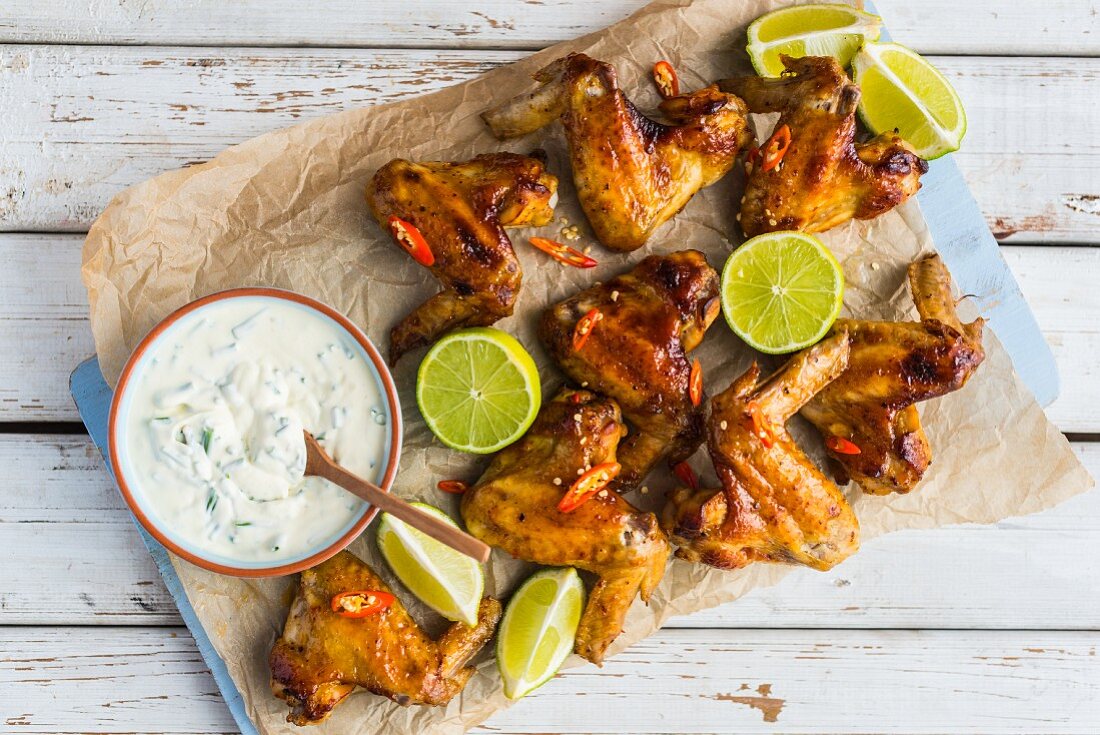 Spicy chicken wings with a dip on baking paper