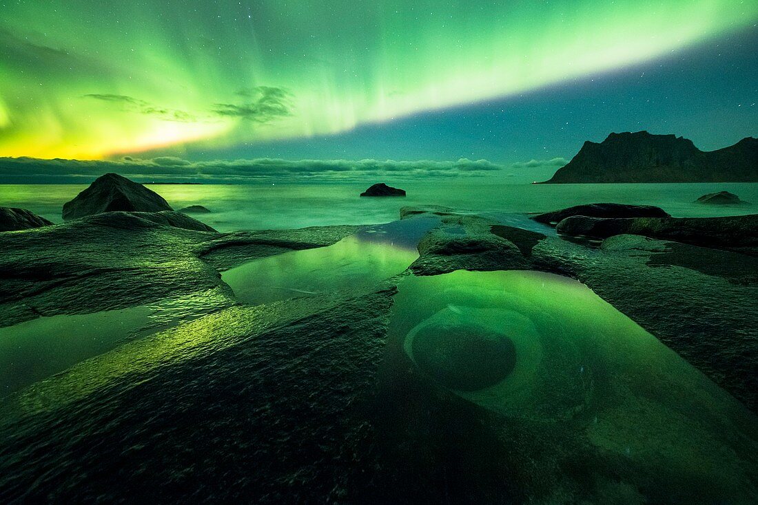 Aurora borealis over coastal rocks