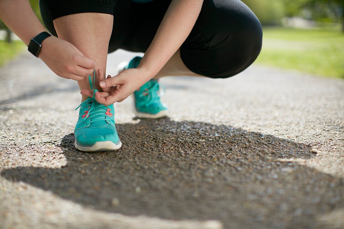 Woman crouching, tying up trainers