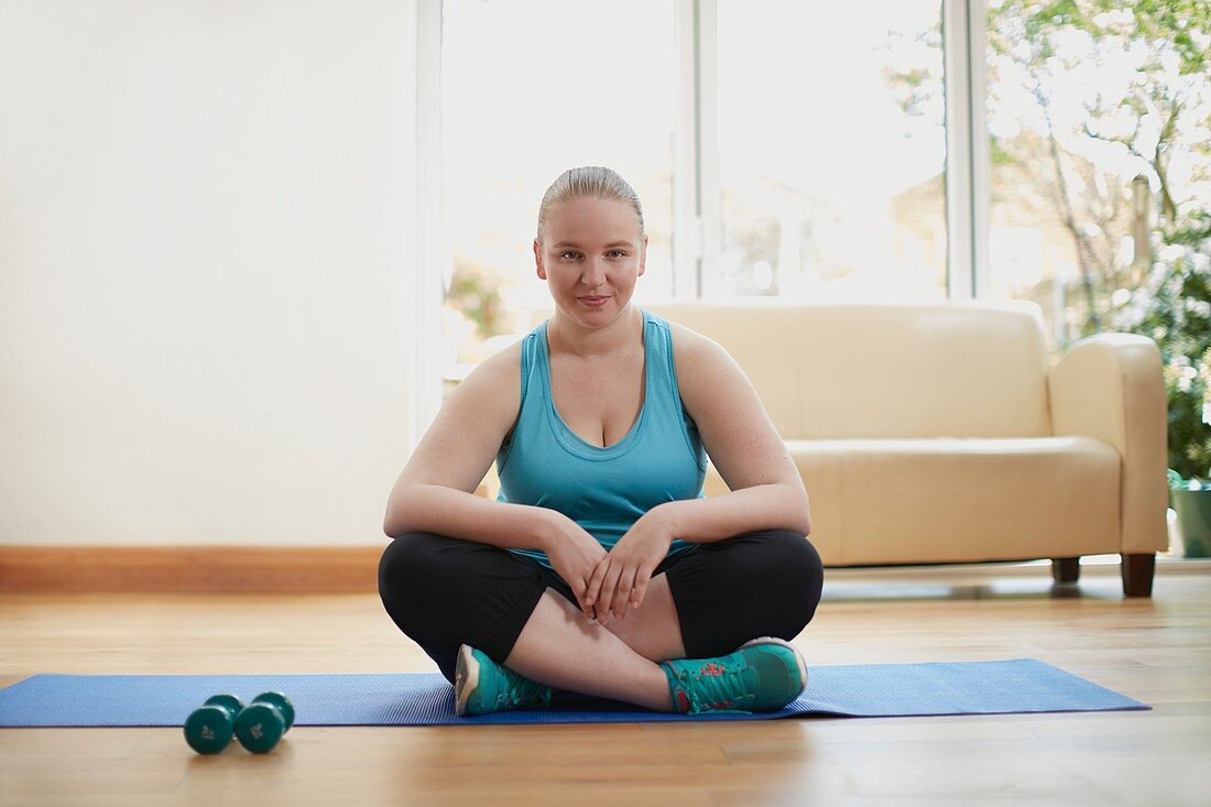 Young woman sitting cross legged on yoga mat