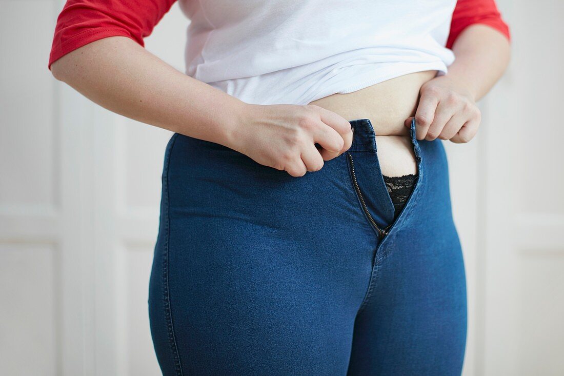 Woman trying to button jeans over tummy