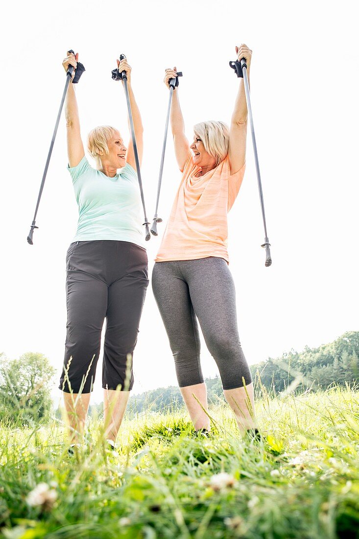 Two women with walking poles raised in air