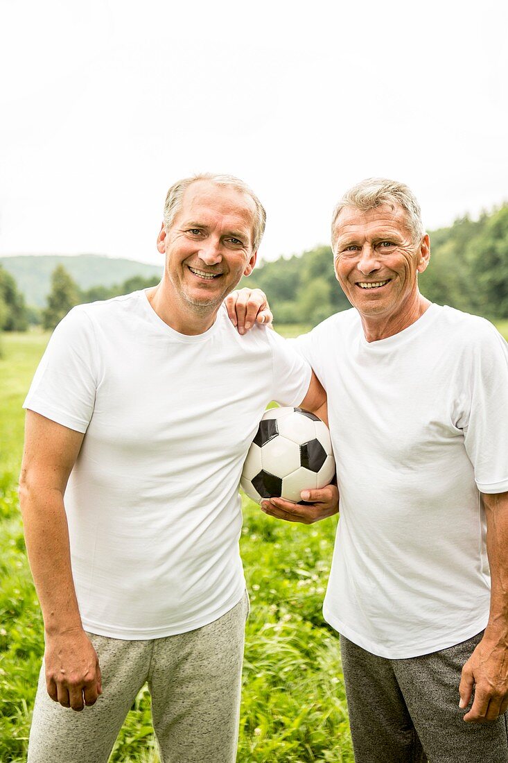 Two men with arms around each other holding football