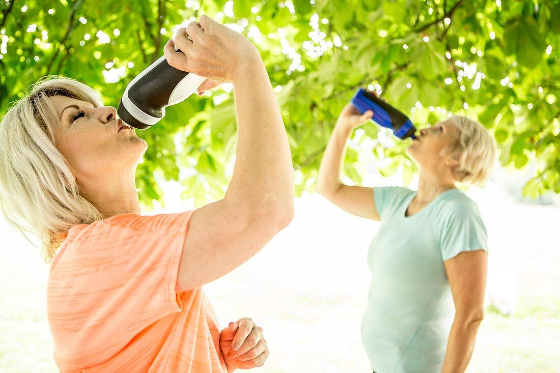 Two women drinking water from sports bottles