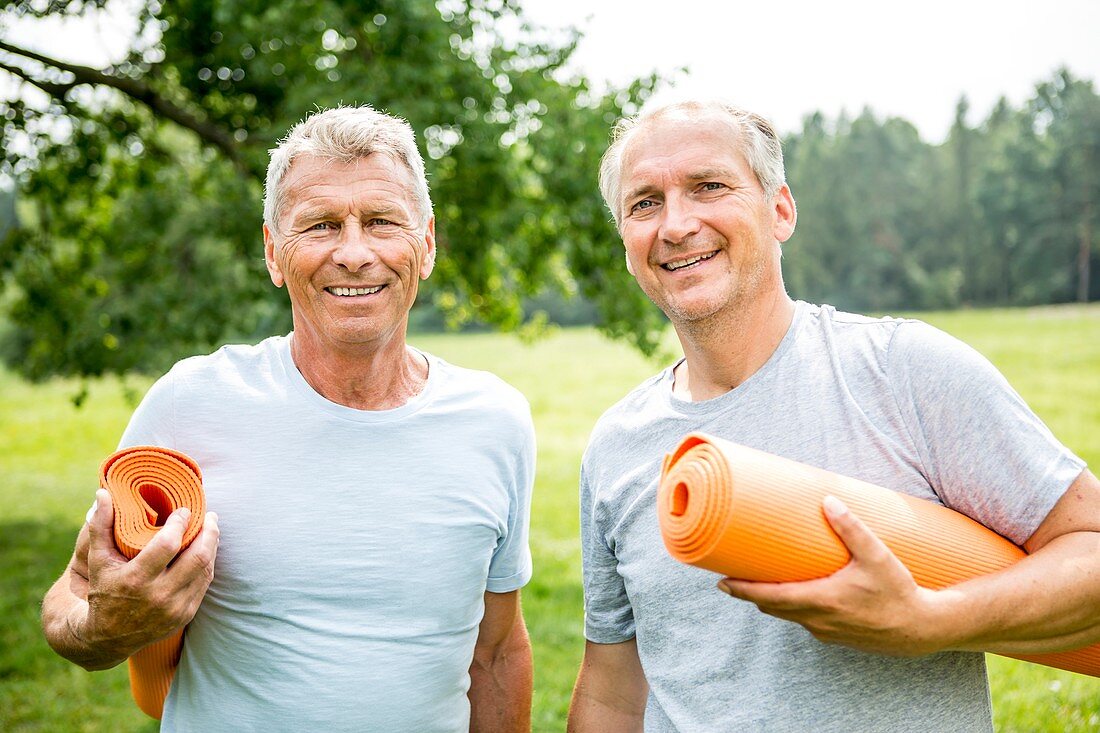 Two men with yoga mats, smiling