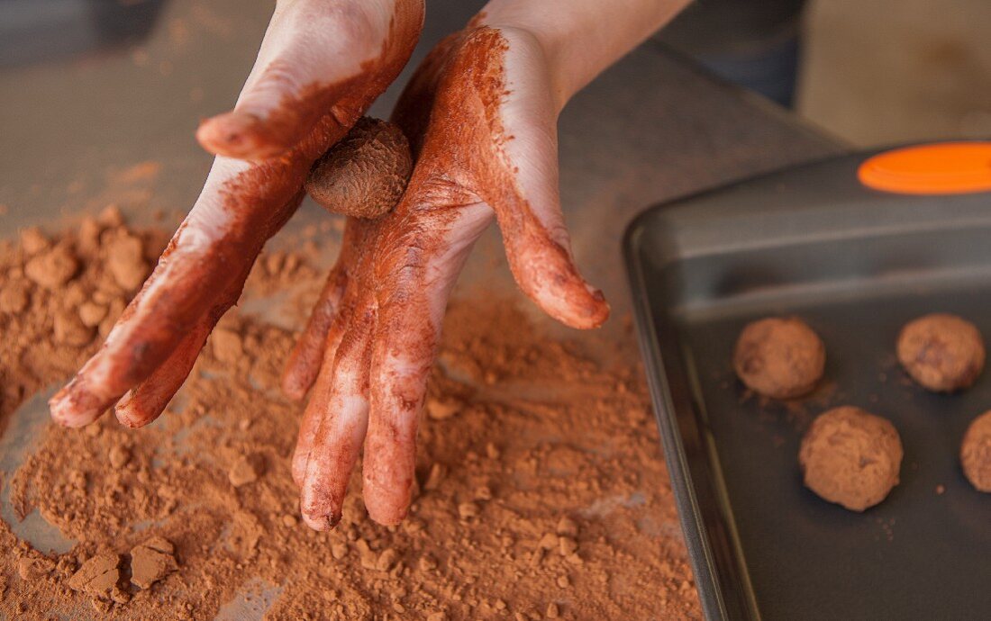 Hands rolling chocolate truffles
