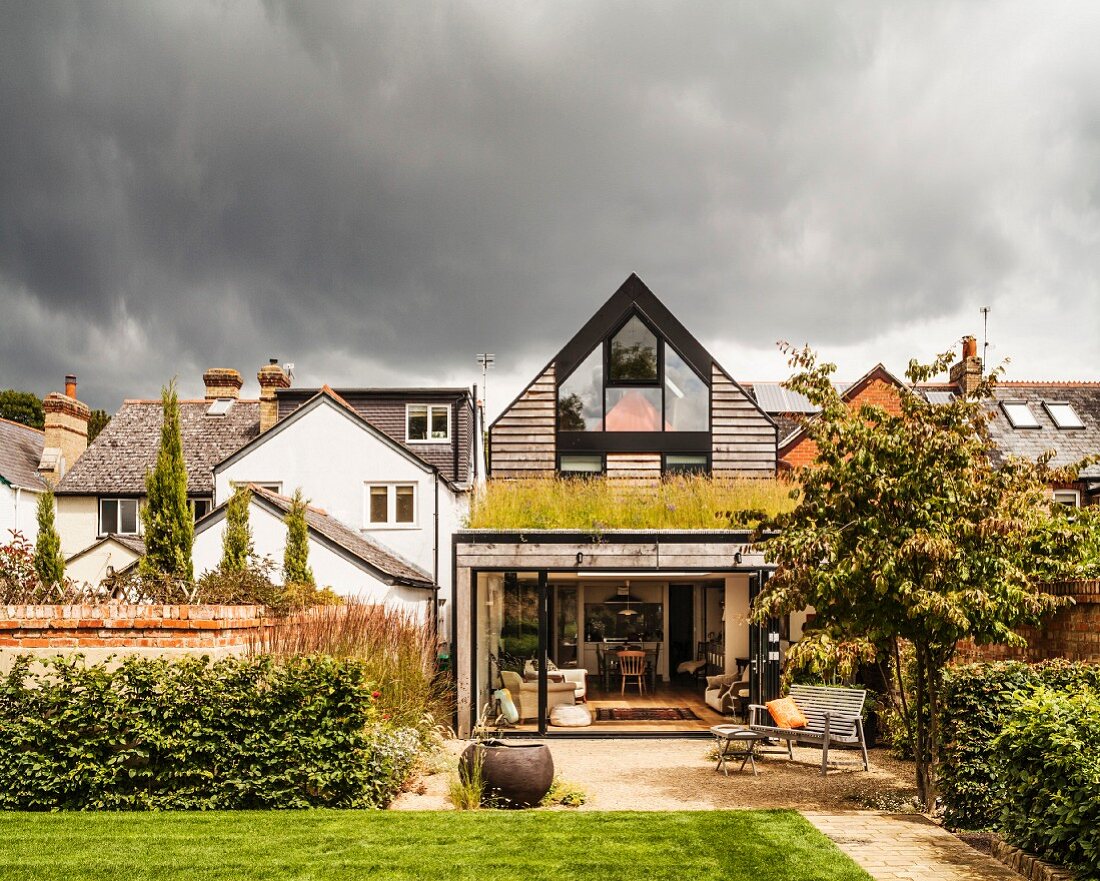 Modern house with gable-end window, green roof on extension and garden