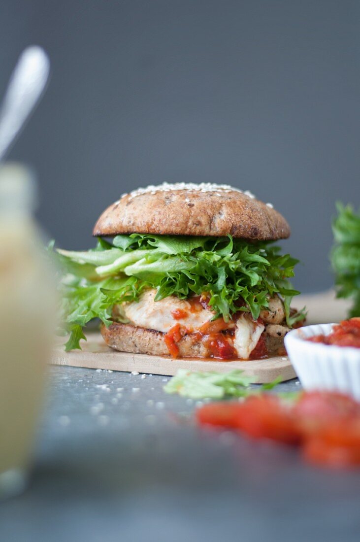 A gourmet chicken burger with mayonnaise and tomatoes