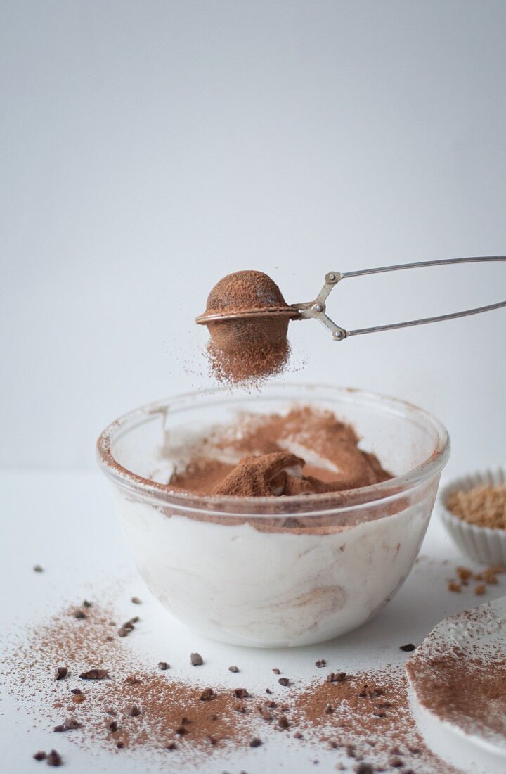 Sifting cocoa powder into a chocolate meringue mixture
