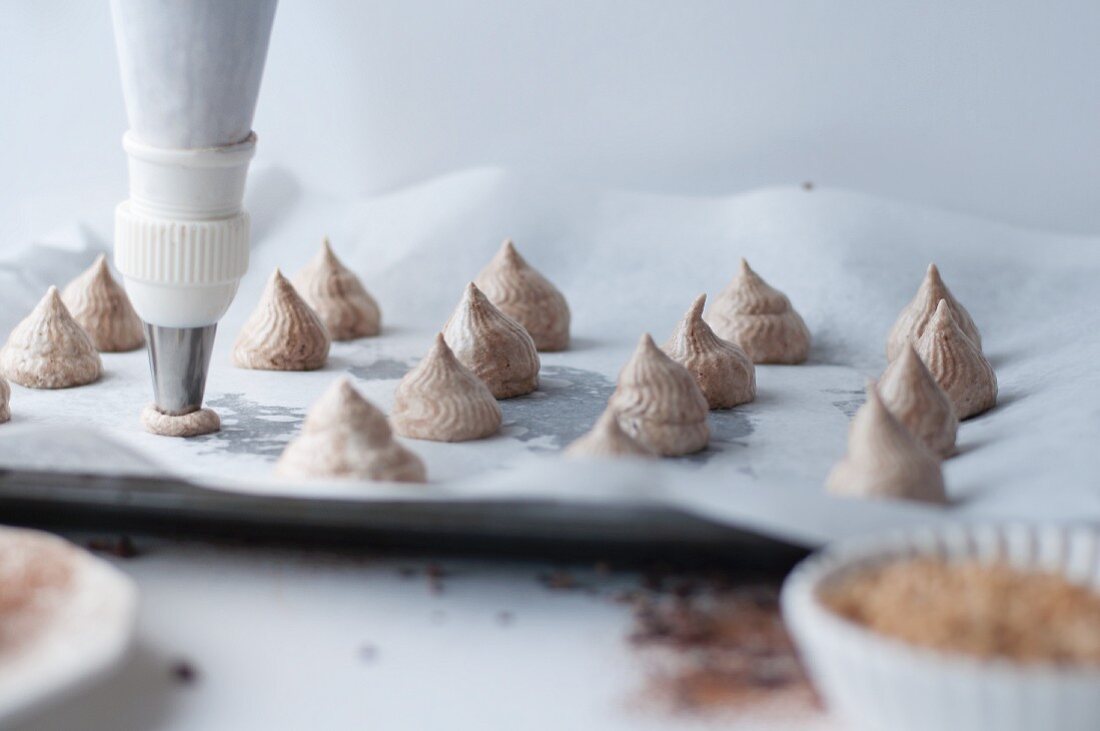 Piping chocolate meringues onto a tray