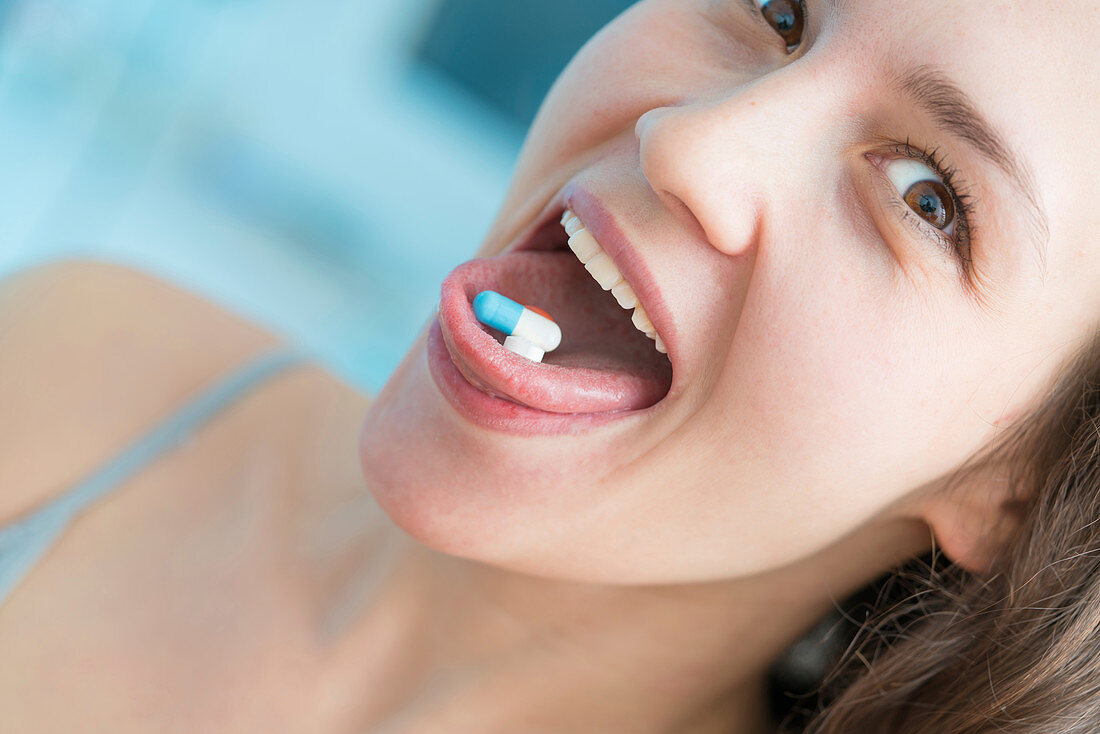 Woman with pills on tongue