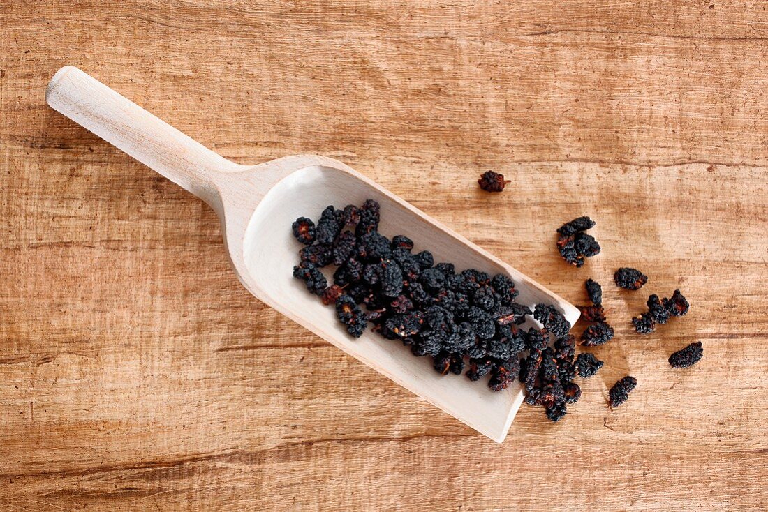 Dried mulberries on a wooden scoop
