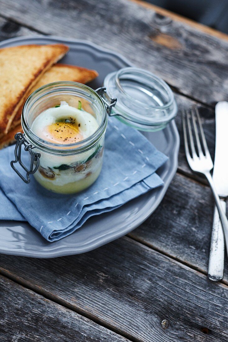 An egg in a glass served with toast