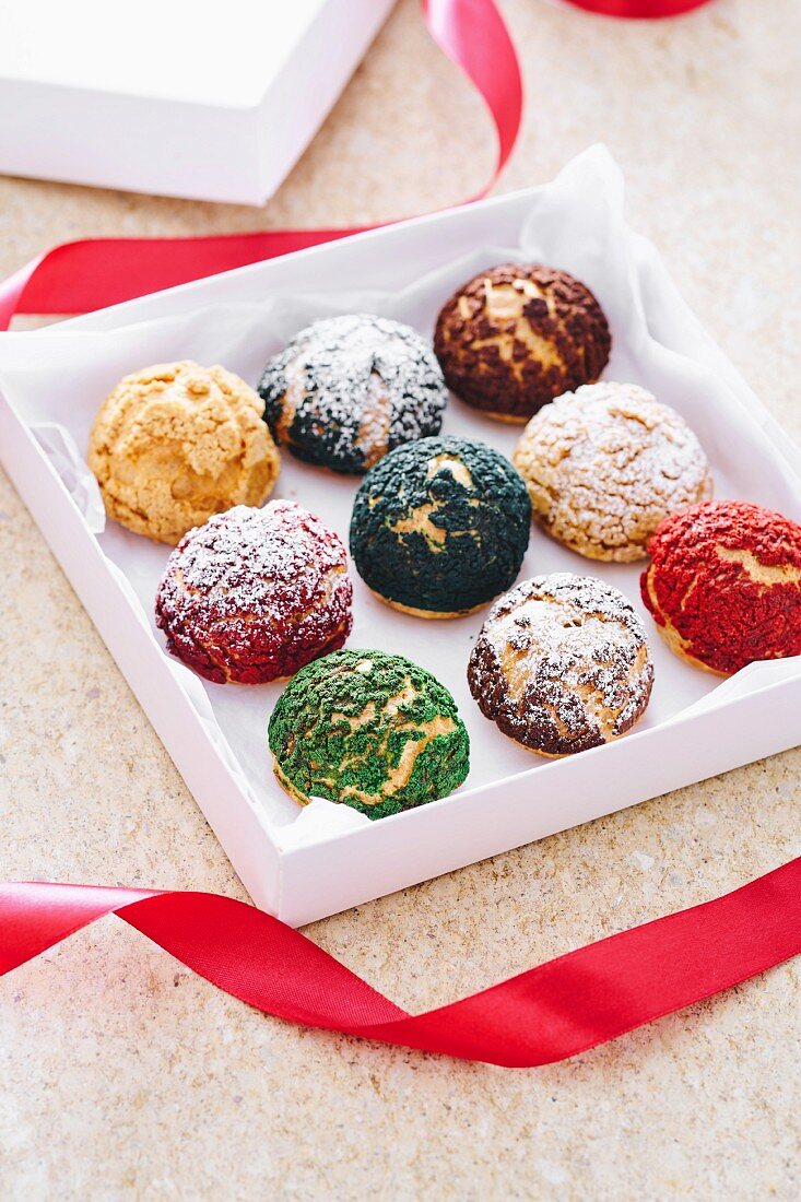 Different-coloured choux pastries in a gift box