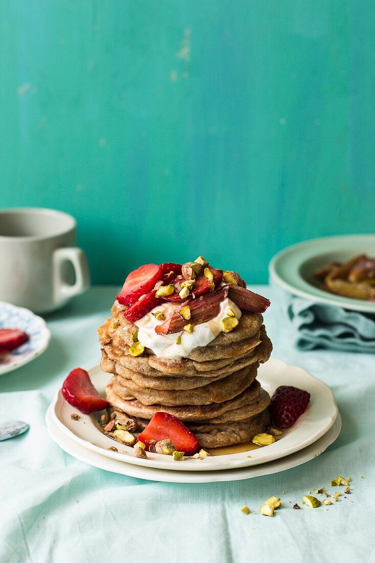 A stack of ricotta pancakes with strawberries, rhubarb and yoghurt