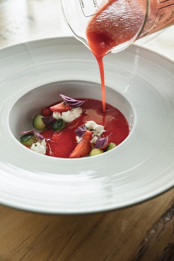Strawberry gazpacho being poured into a soup bowl