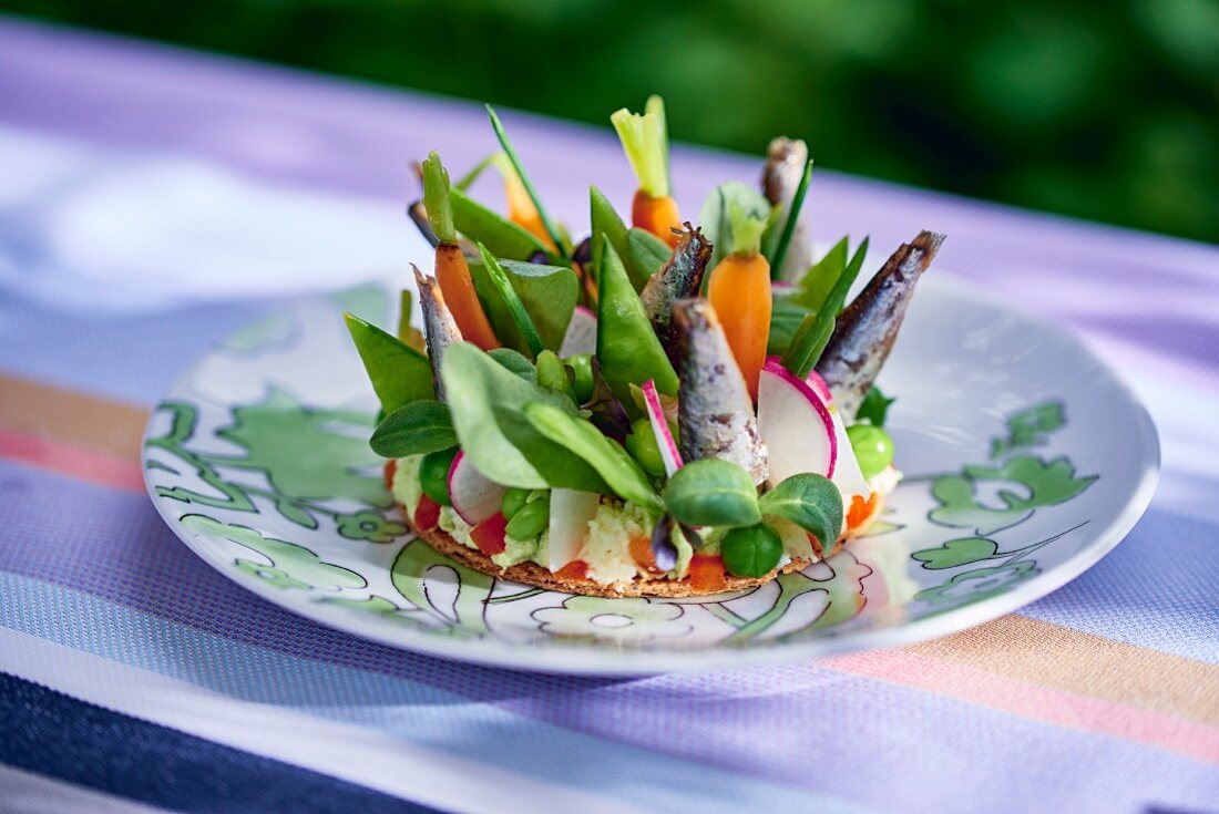 A vegetable tart with sardines on a table outdoors