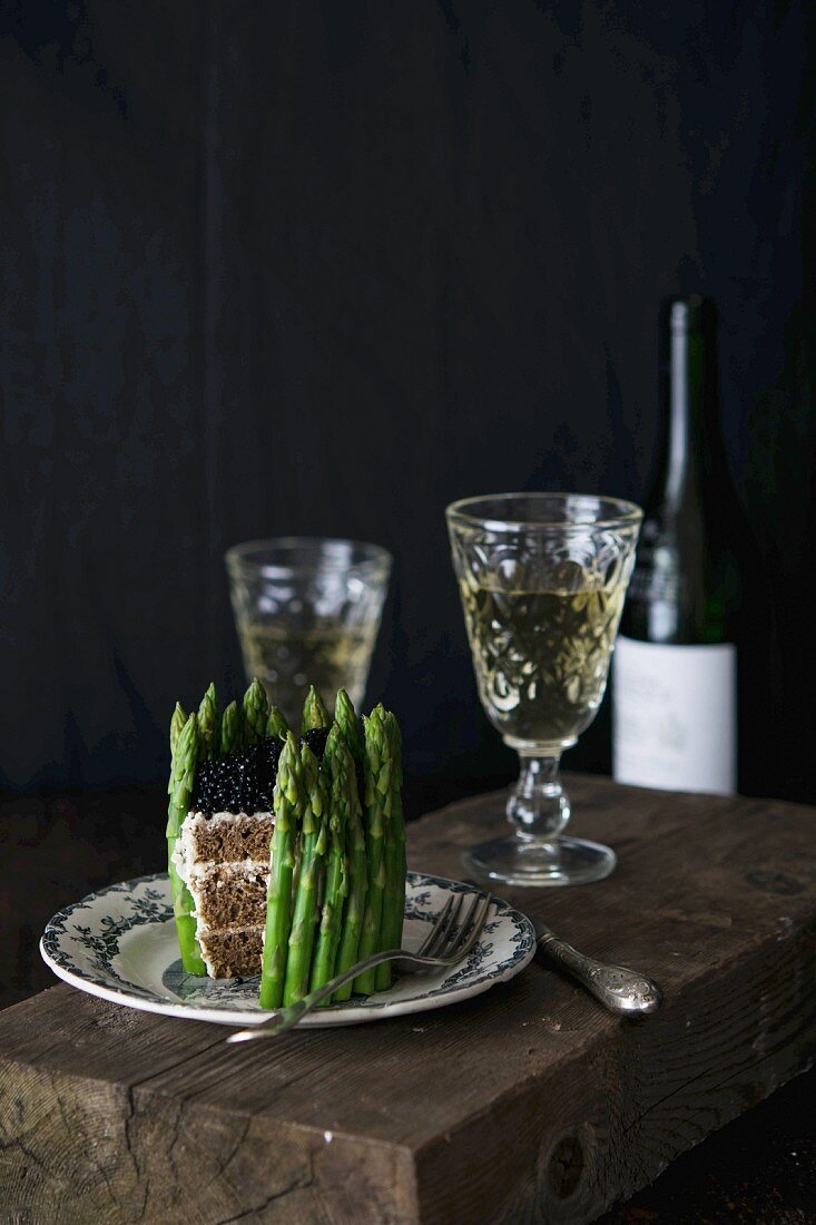 A sandwich cake with green asparagus served with white wine