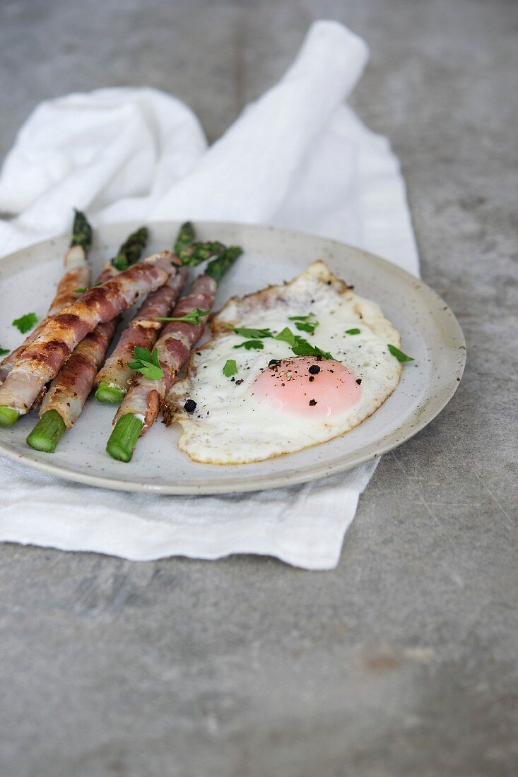 Bacon-wrapped green asparagus served with a fried egg