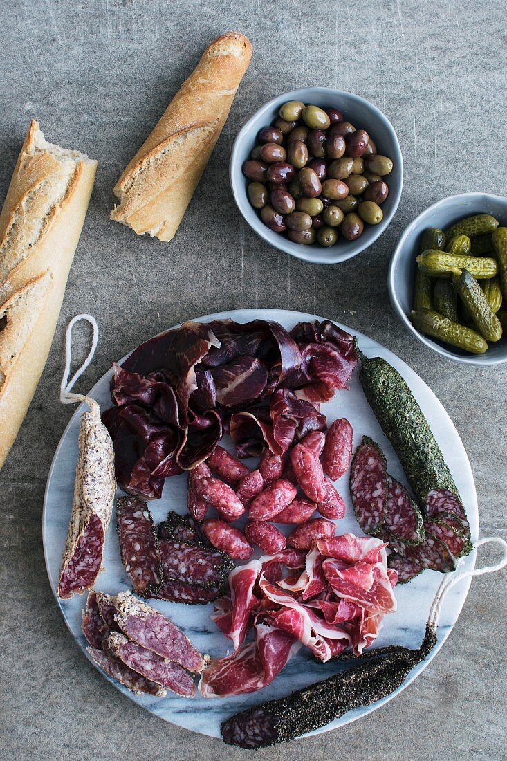 Tapasplatte mit Schinken und Wurst, dazu Brot, Oliven und Cornichons (Spanien)