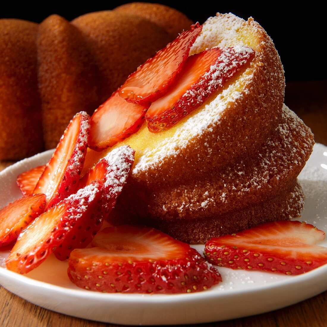 Bundt Cake with sliced strawberries and powdered sugar
