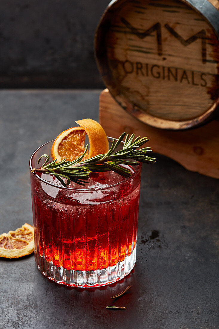 A cocktail with rosemary and dried orange slices