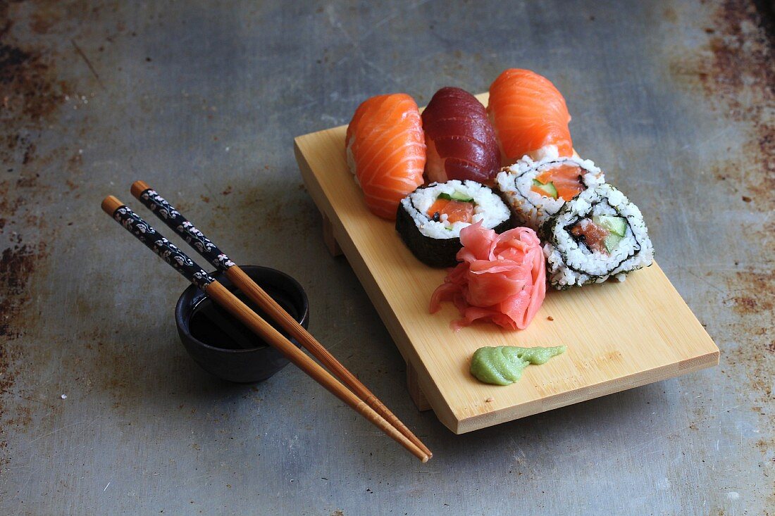 A sushi board with wasabi, ginger and soy sauce