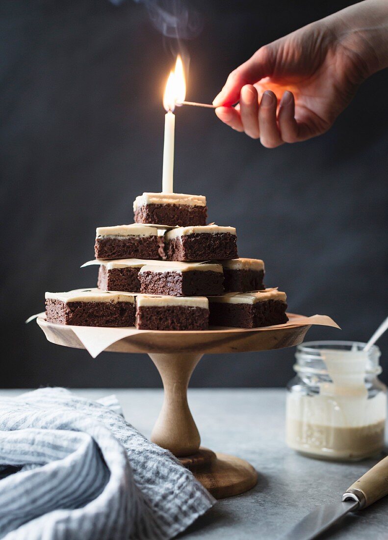 Brennende Kerze auf pyramidenförmig gestapelten glutenfreien Brownies