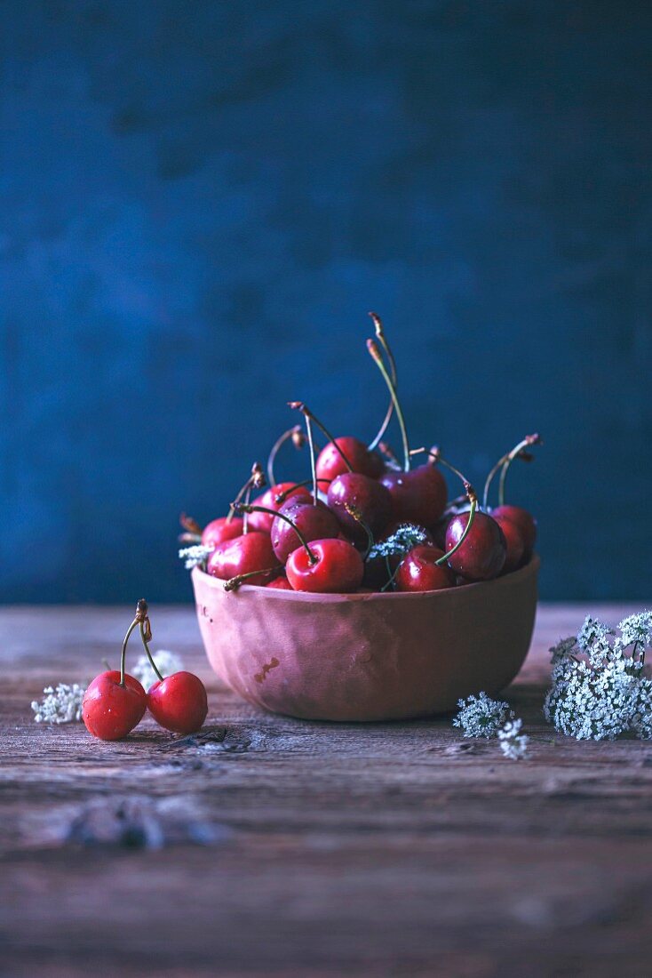 Fresh cherries in a ceramic bowl on a rustic wooden table