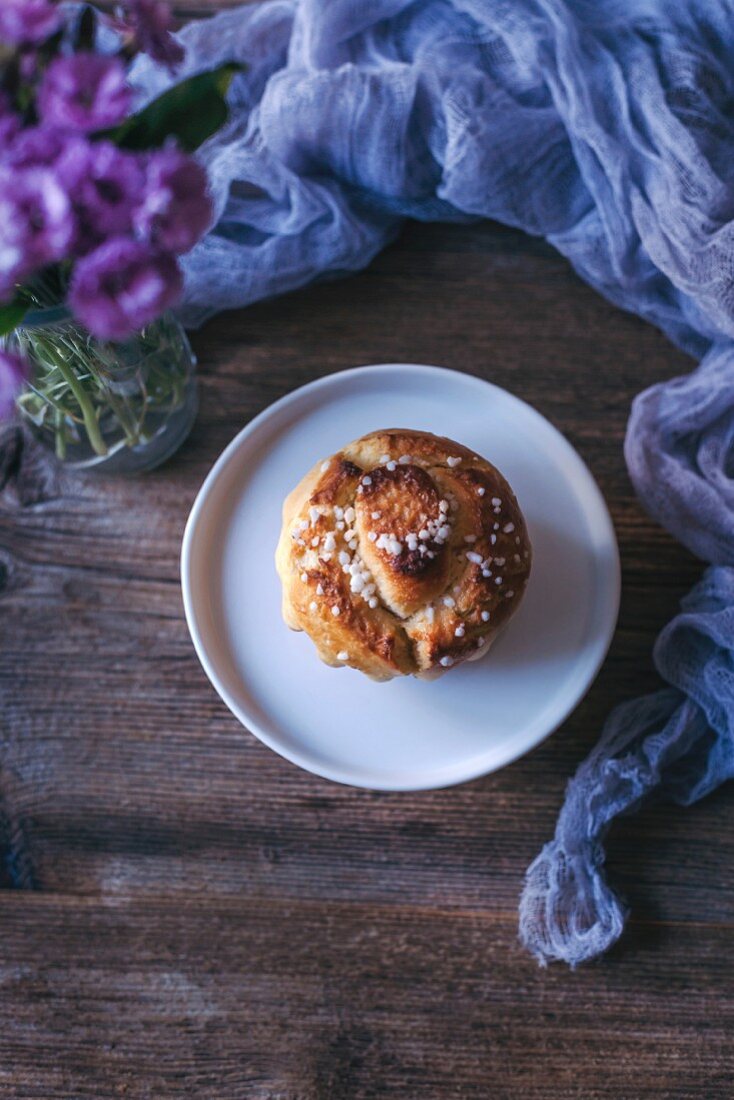 Brioche mit Hagelzucker auf Teller und Holztisch (Aufsicht)