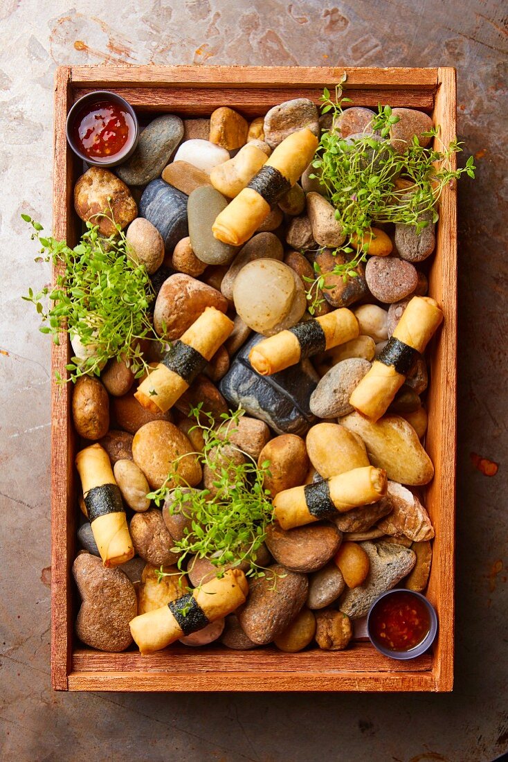 Spring rolls served on a wooden tray with stones (Asia)