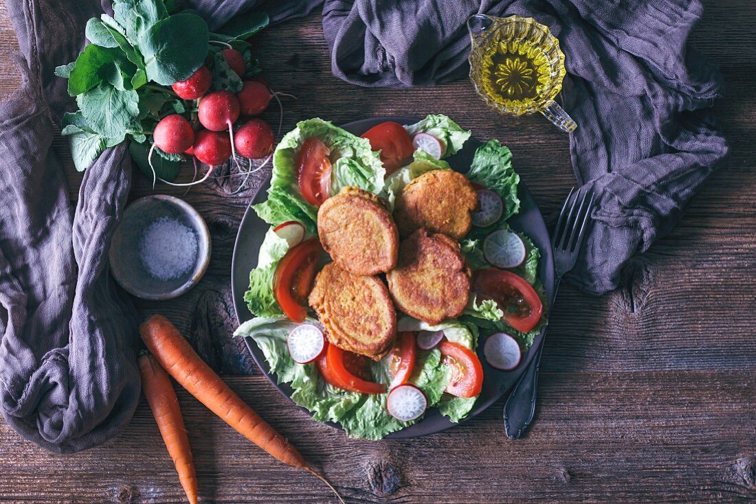 Vegetarische Kichererbsen-Fritters auf Blattsalat mit Tomaten und Radieschen