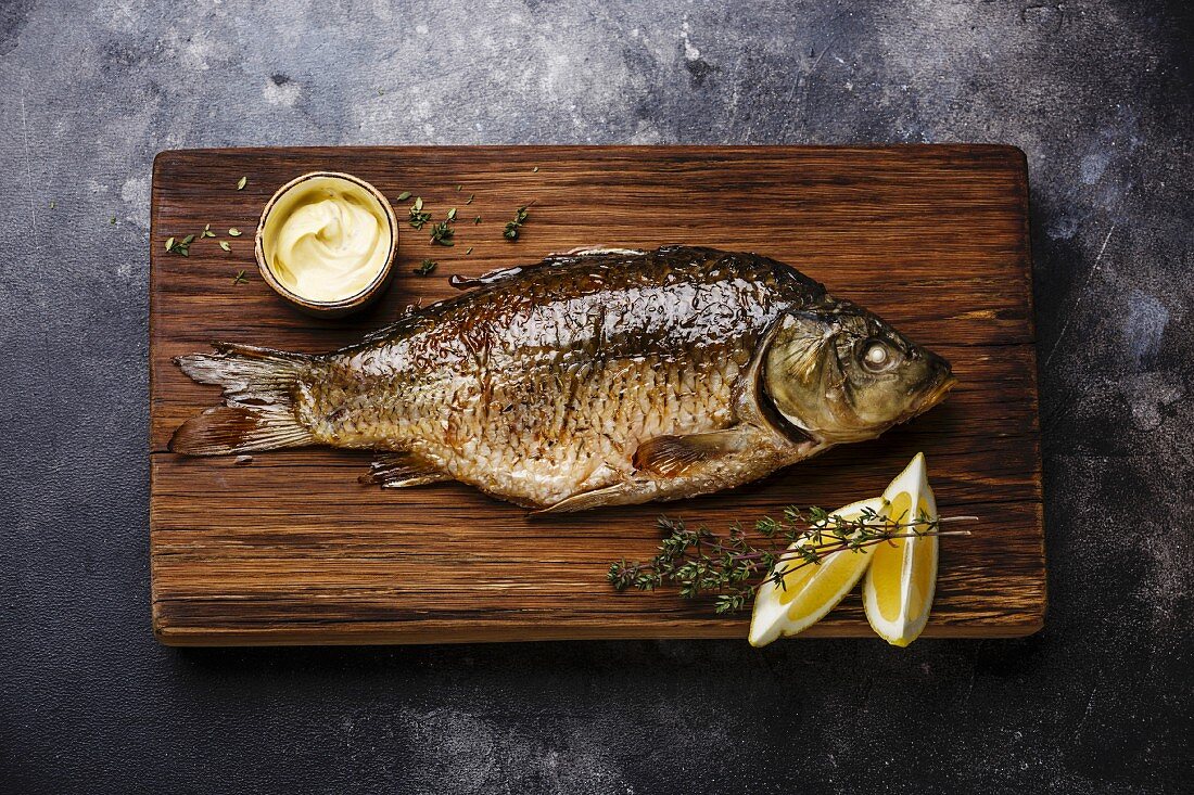 Baked carp with lemon and sauce on cutting board