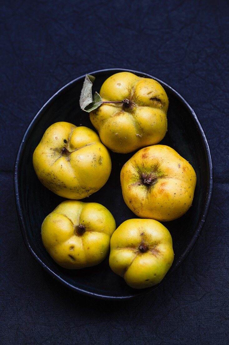 Several quinces in a black bowl