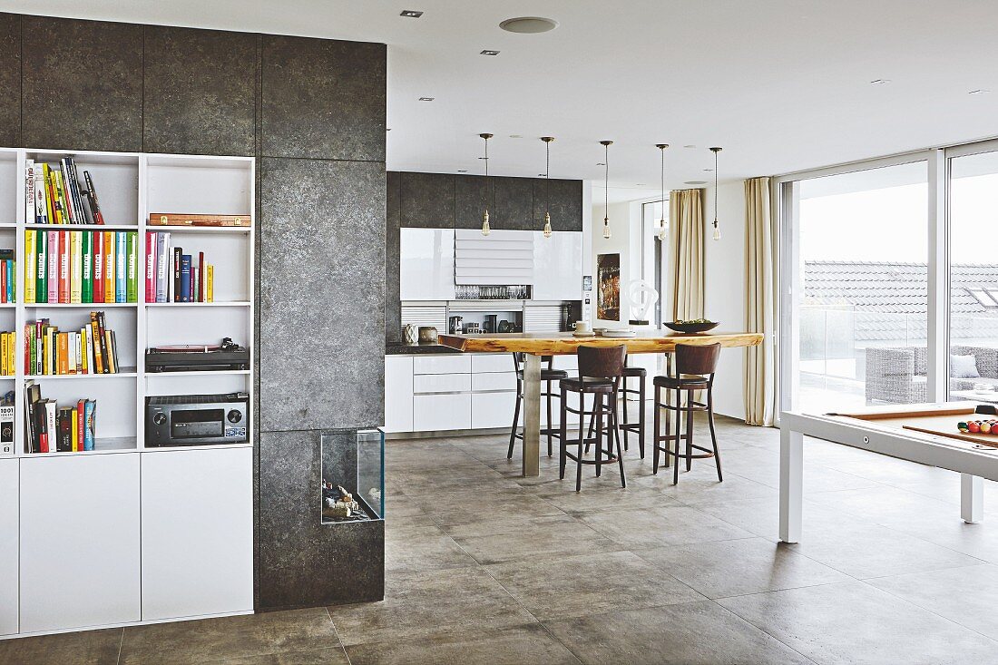 White built-in shelves framed by a coated wall and gas fire with views into an open-plan kitchen