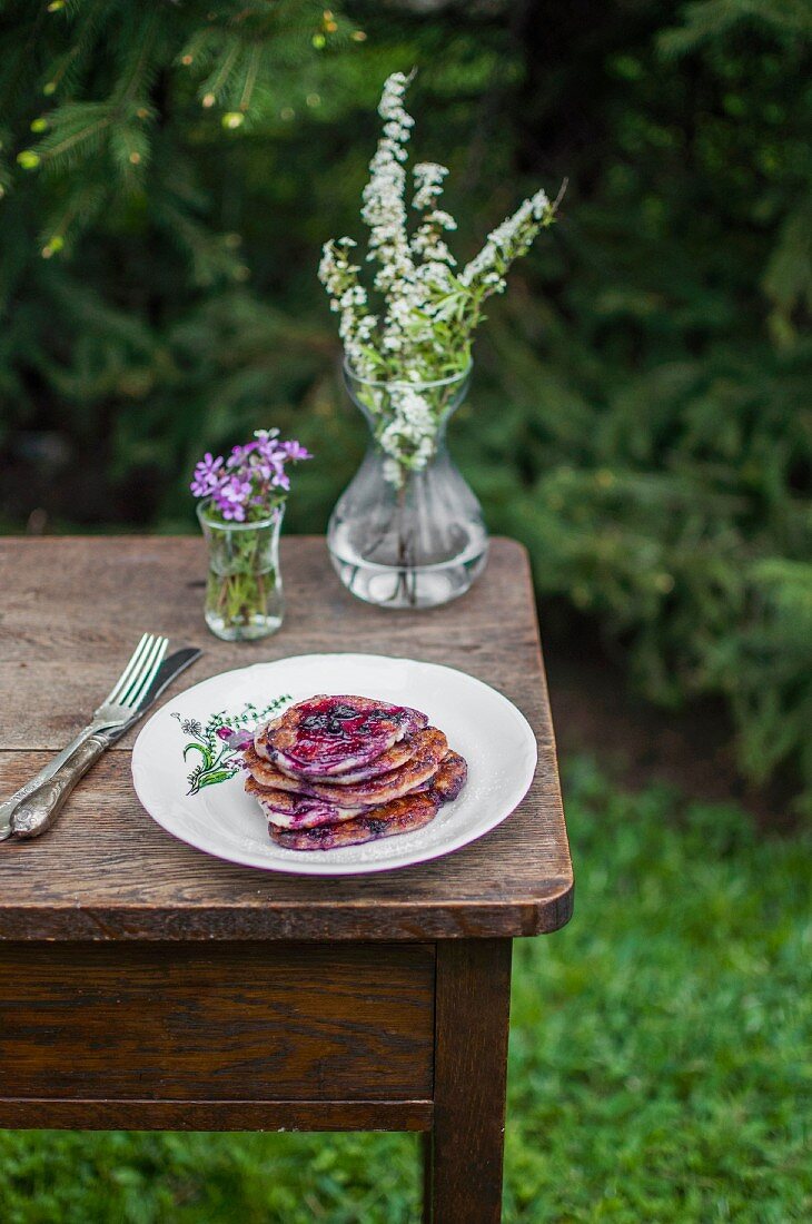 Pancakes with blueberries and blueberry sauce, served in the garden