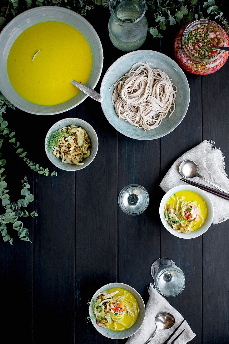 Golden Fennel Soba Noodle Soup is served with quick pickled veggies and white wine on a black wooden background