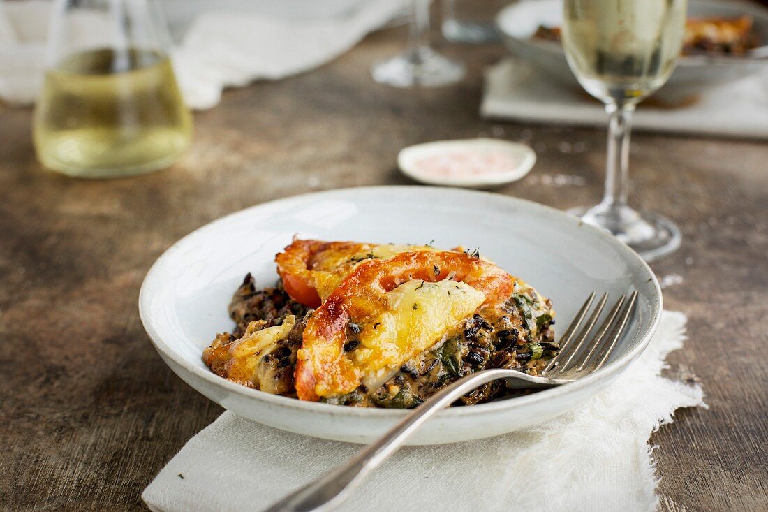 Wildreisauflauf mit Grünkohl, Tomaten und Cheddarkäse serviert mit Weißwein