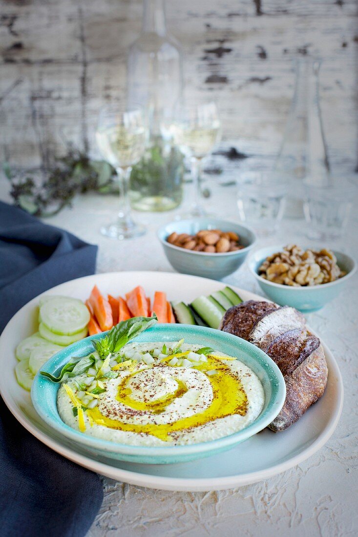 Hummus mit Meyer-Zitronen und Basilikum serviert mit Gemüse, Brot und Weißwein