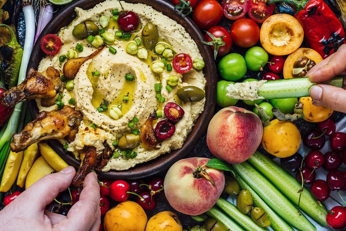 Vorspeisenplatte mit Hummus-Dip, Hühnerflügeln, Kirschen, Kichererbsen und Oliven