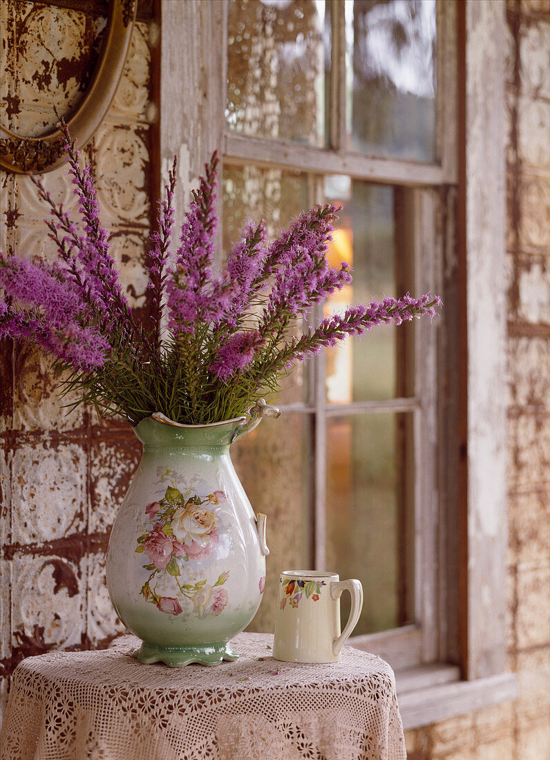 Vintage-style vase of flowers against battered wall