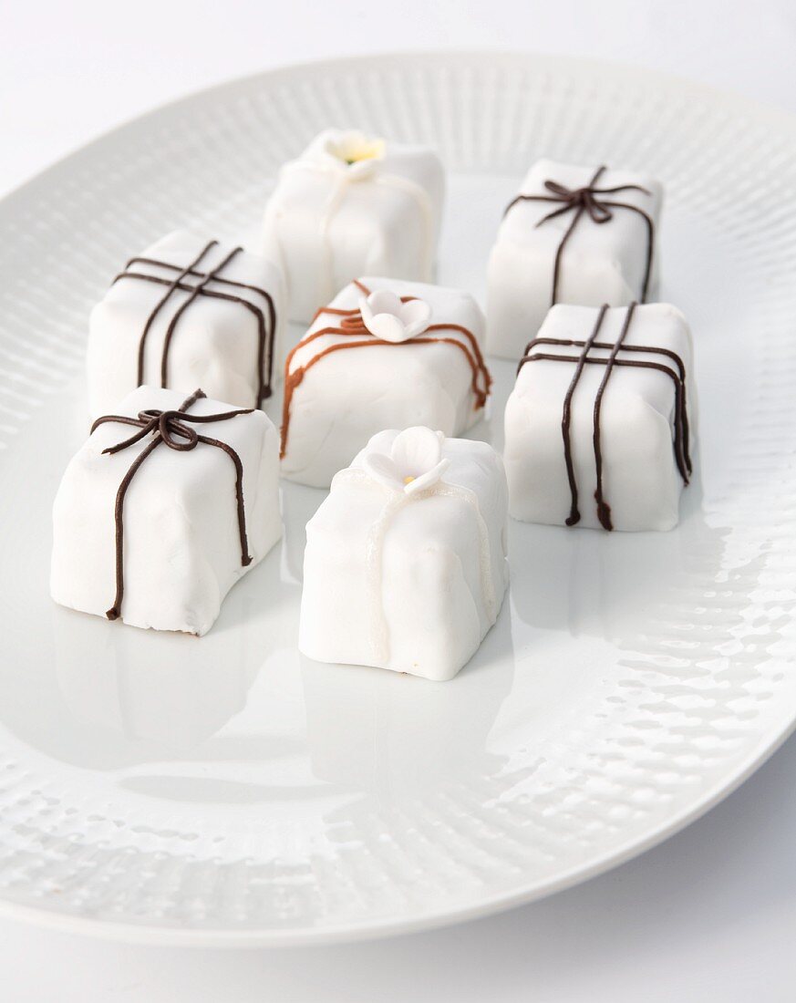 White petit fours decorated with chocolate icing and sugar flowers