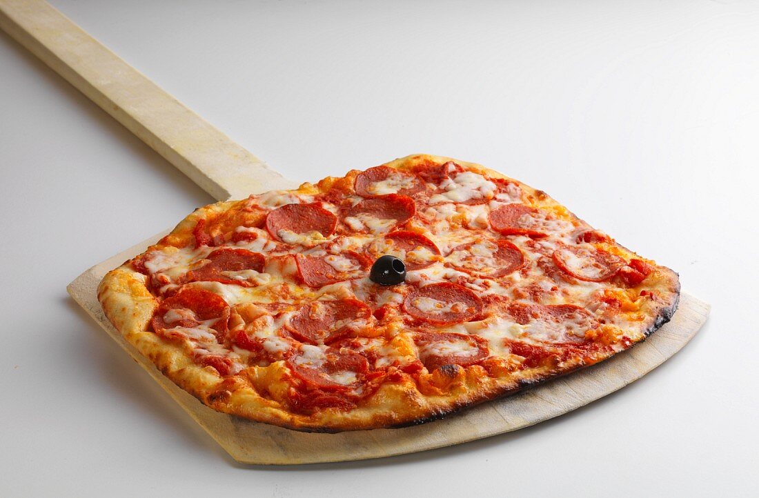 A pizza with pepperoni on a pizza plate