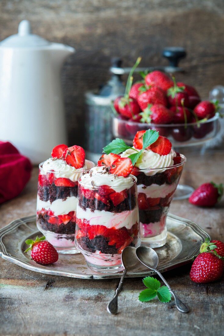 Strawberry trifles with mascarpone cream and chocolate biscuits in dessert glasses