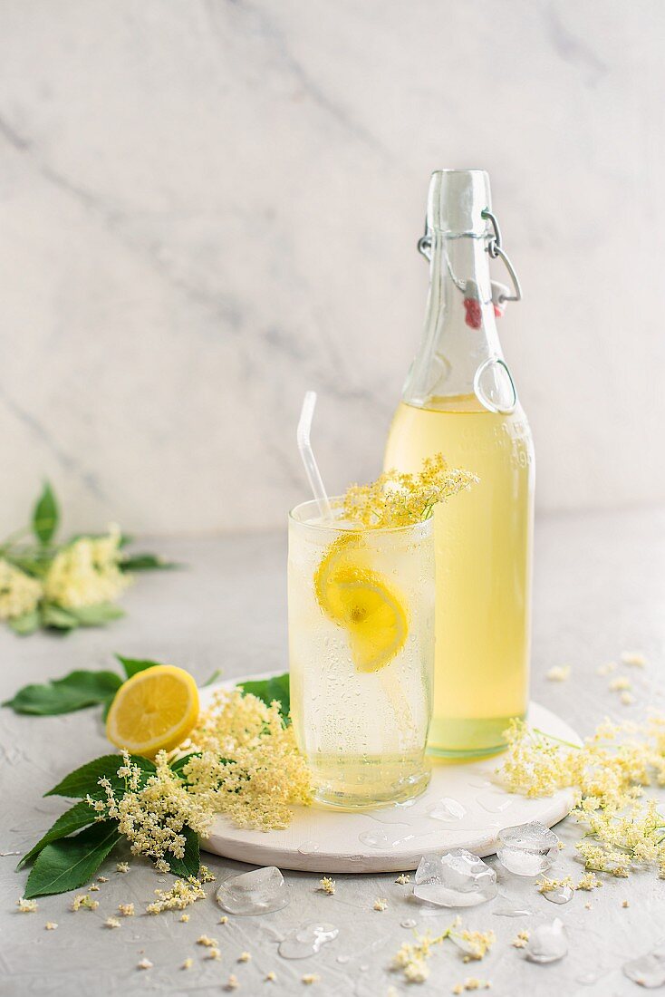Homemade elderflower cordial in a glass with fresh lemon and ice